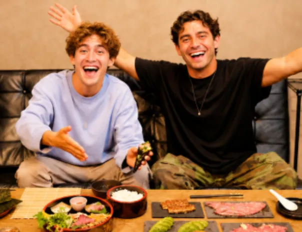Two smiling participants with hand-rolled sushi at the table